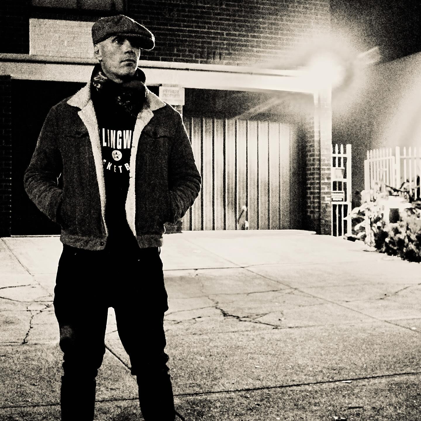 Brian El Dorado — black-and-white night portrait, flat cap and sherpa-collared jacket