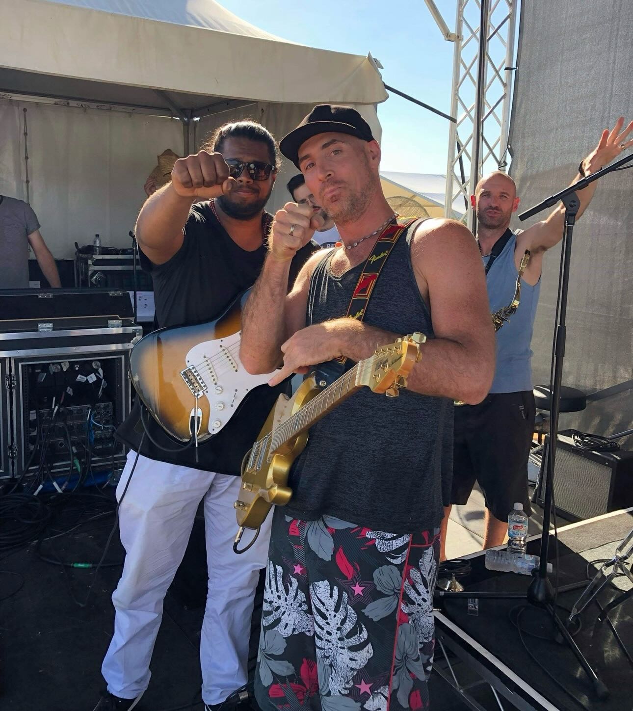 Brian El Dorado on stage at a festival — guitar, daylight, bandmate fist out