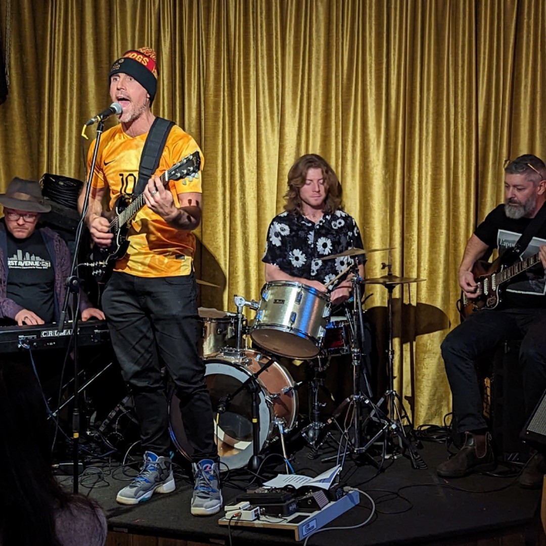 Brian El Dorado mid-performance — yellow jersey, full band on stage