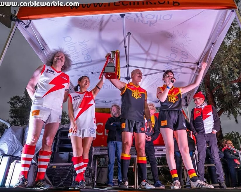 Brian lifting the Reclink Community Cup trophy on the Victoria Park podium alongside teammates